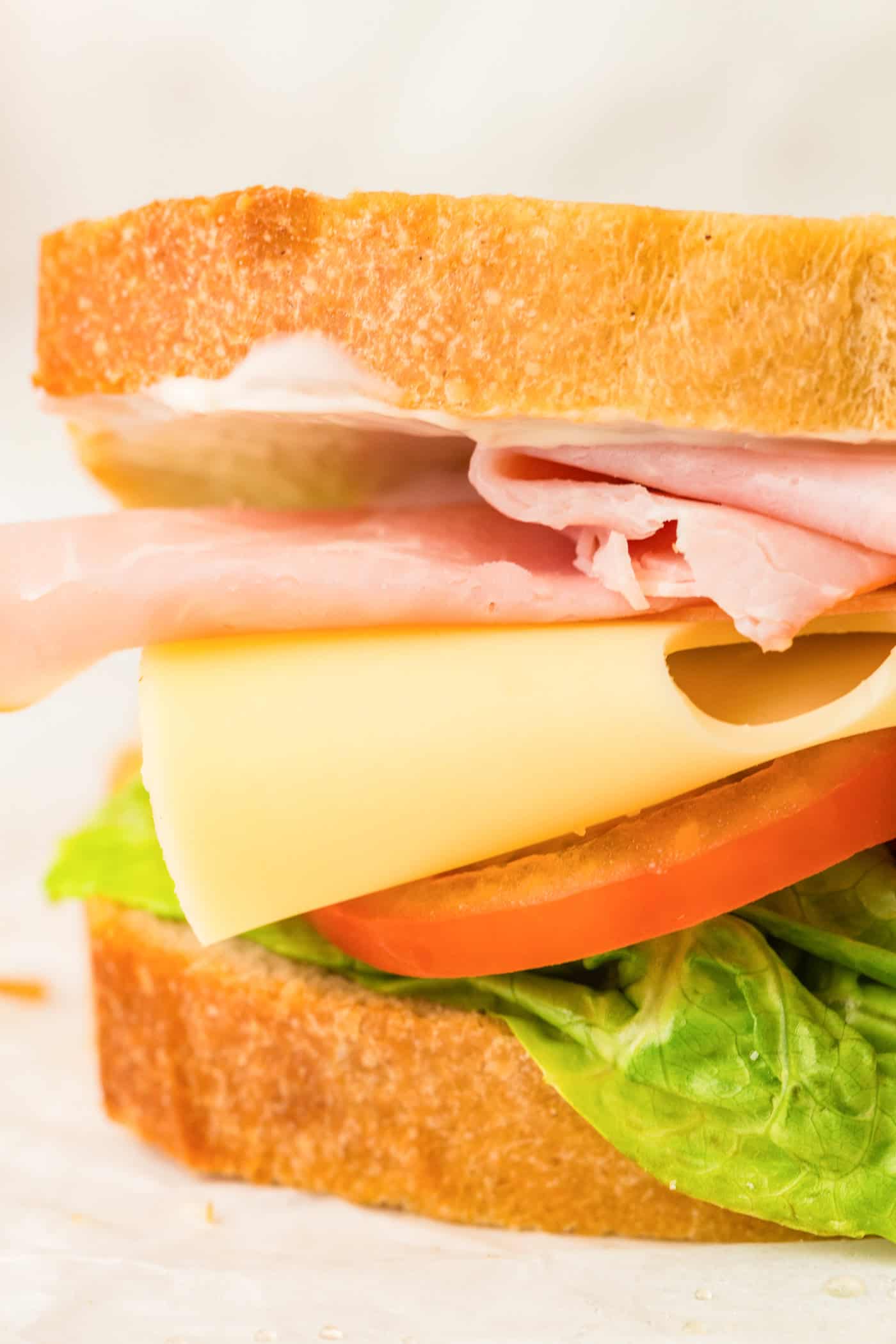 a thick sandwich with Swiss cheese, tomatoes, and meat made on sourdough sandwich bread