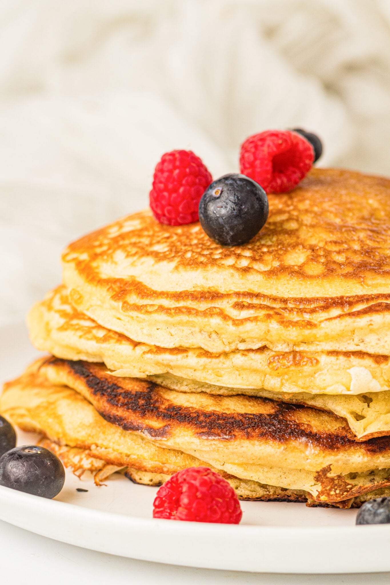 fluffy sourdough discard pancakes with blueberries and raspberries on top