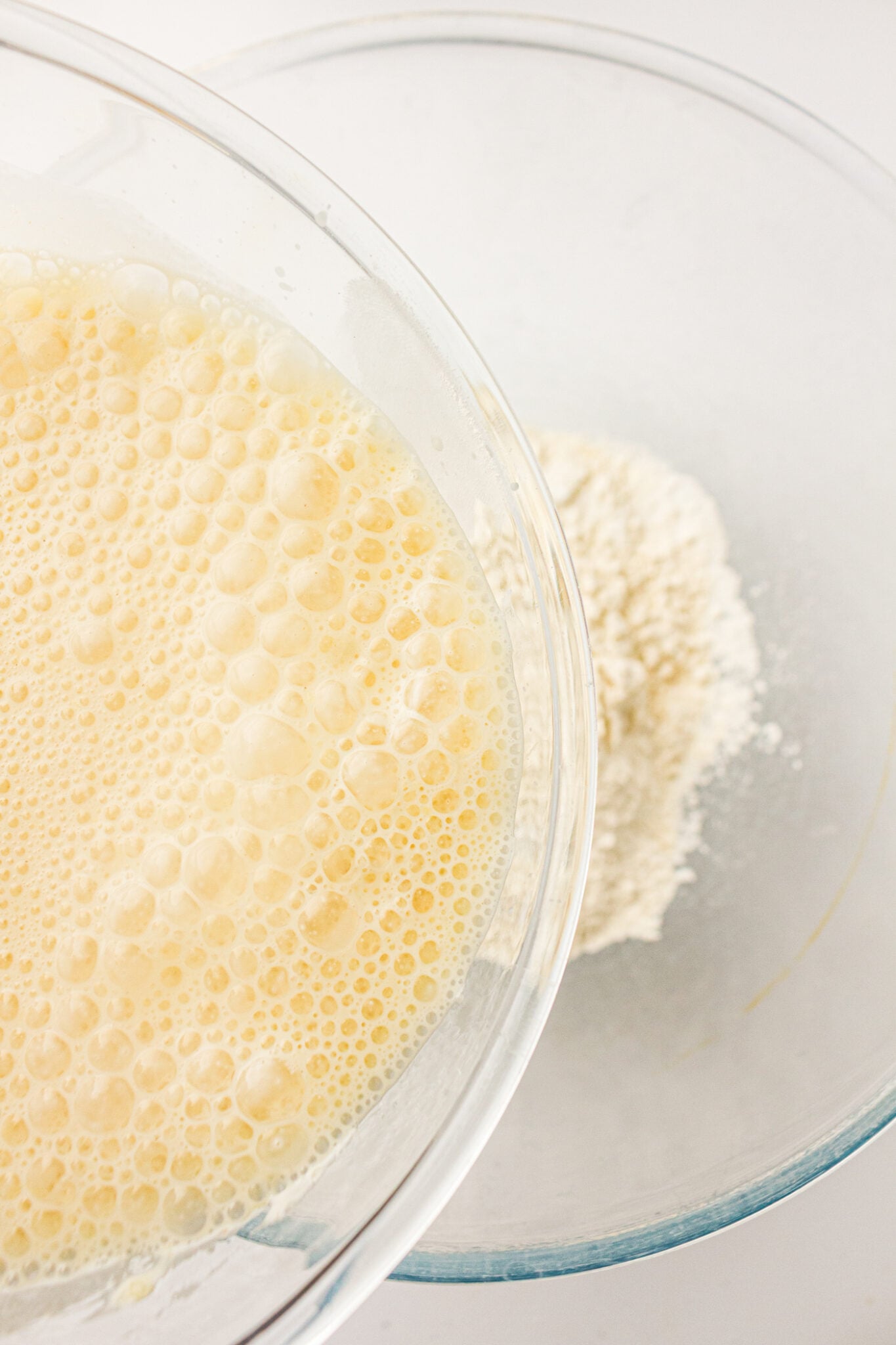 pouring mixed wet ingredients for sourdough discard pancakes into a bowl with the dry ingredients