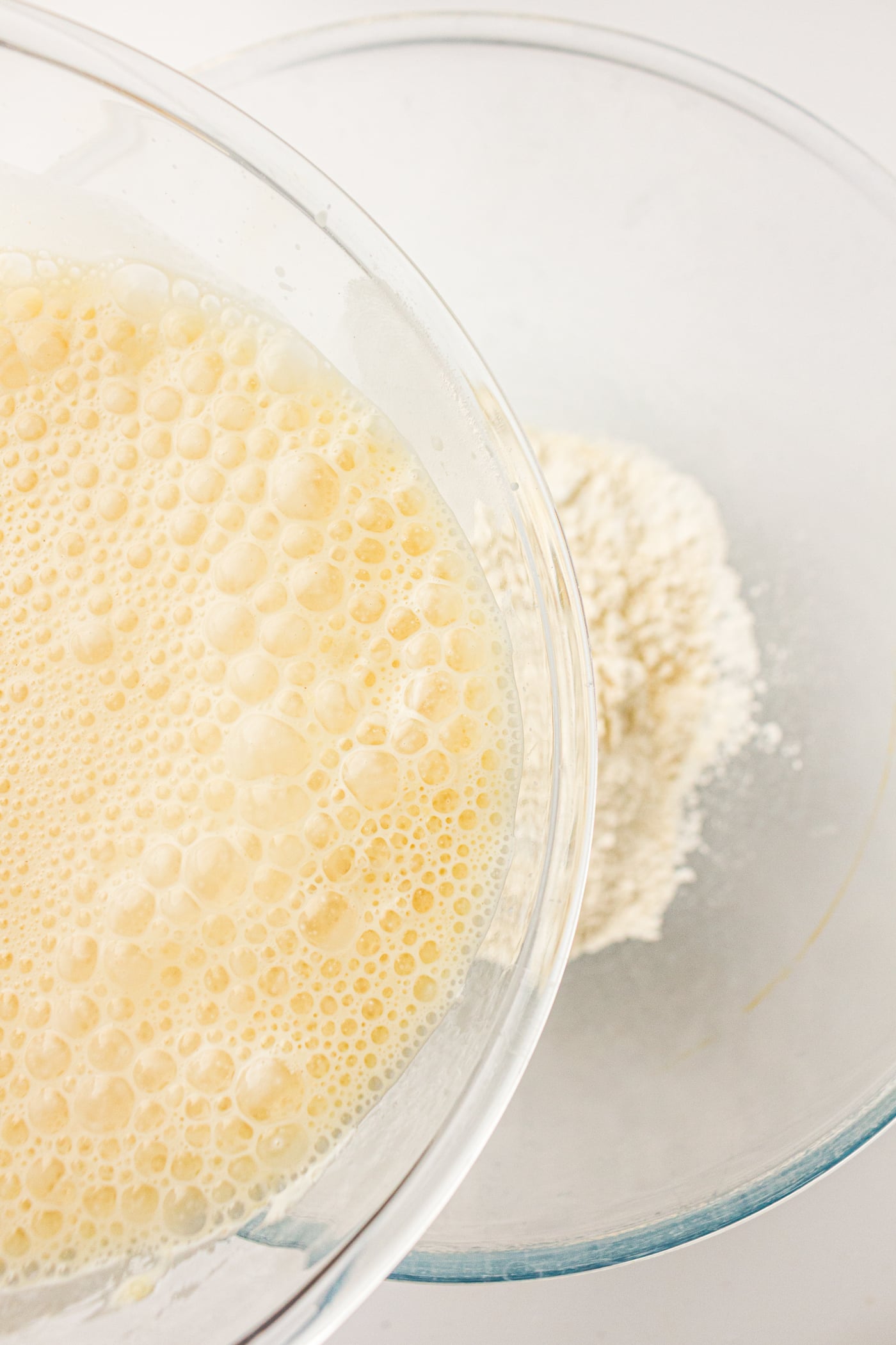 pouring mixed wet ingredients for sourdough discard pancakes into a bowl with the dry ingredients
