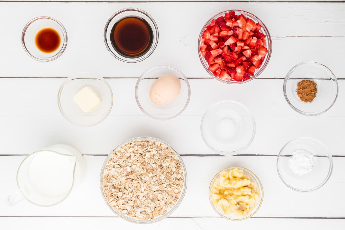 ingredients for strawberry baked oatmeal including strawberries, oatmeal, bananas, honey, vanilla, and baking soda