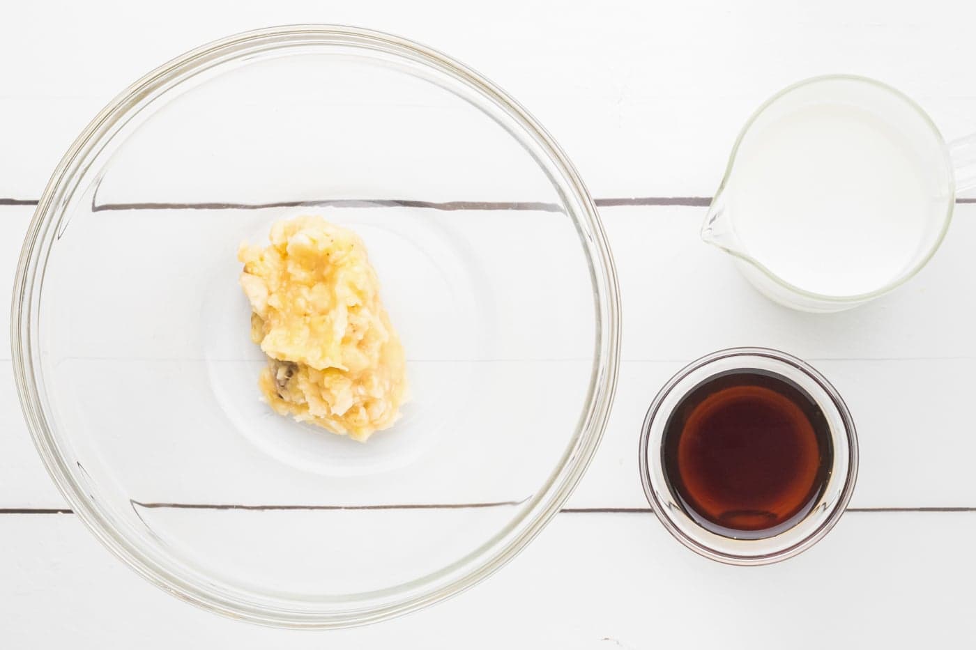 a bowl with mashed banana next to milk and honey