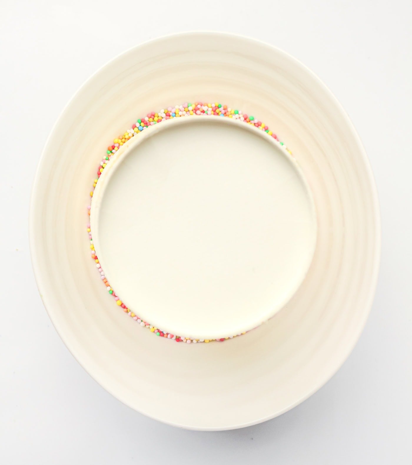 a paper cup with a gluten free dot cake getting sprinkles