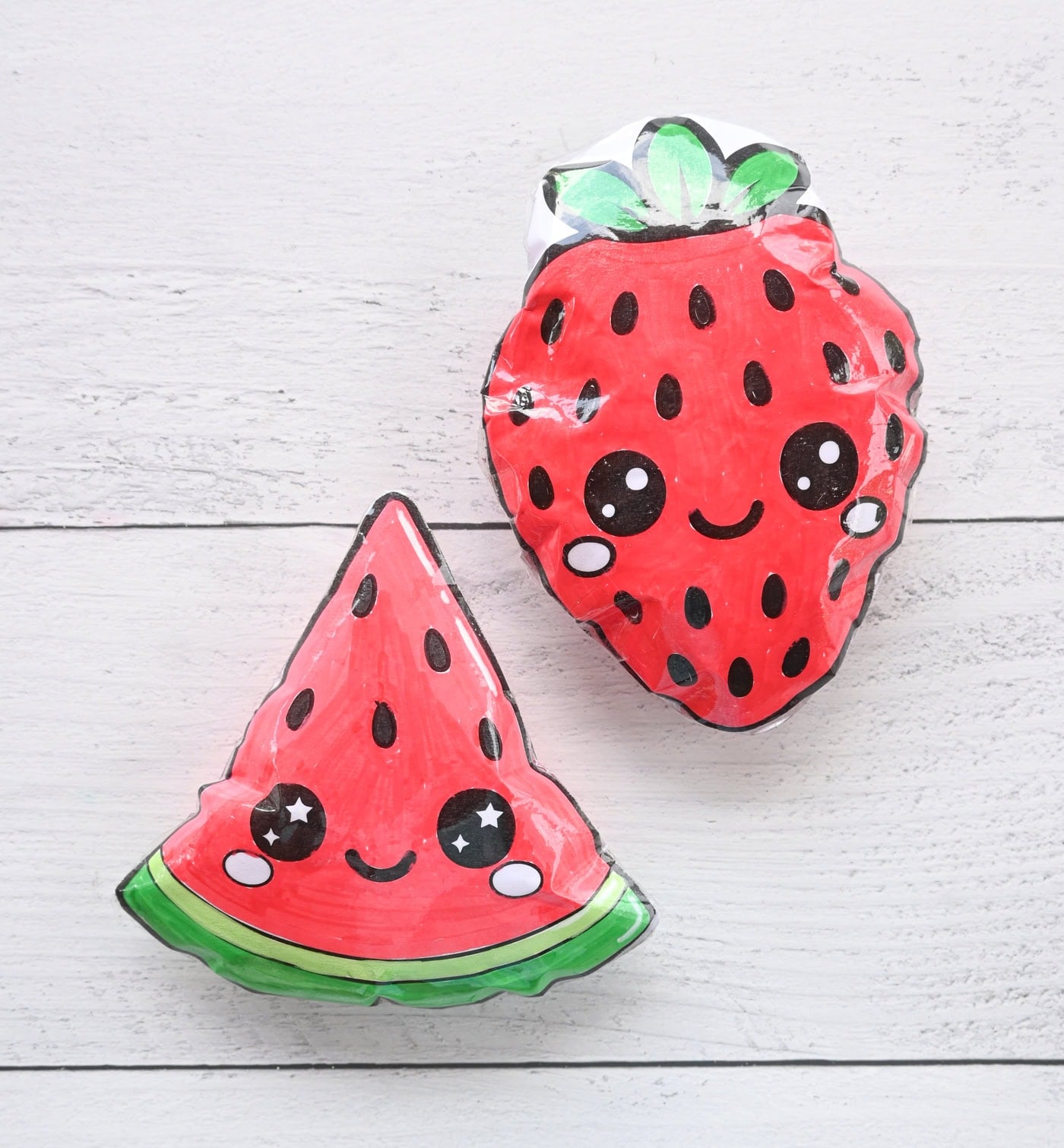 a paper squishy watermelon and as strawberry on a white surface