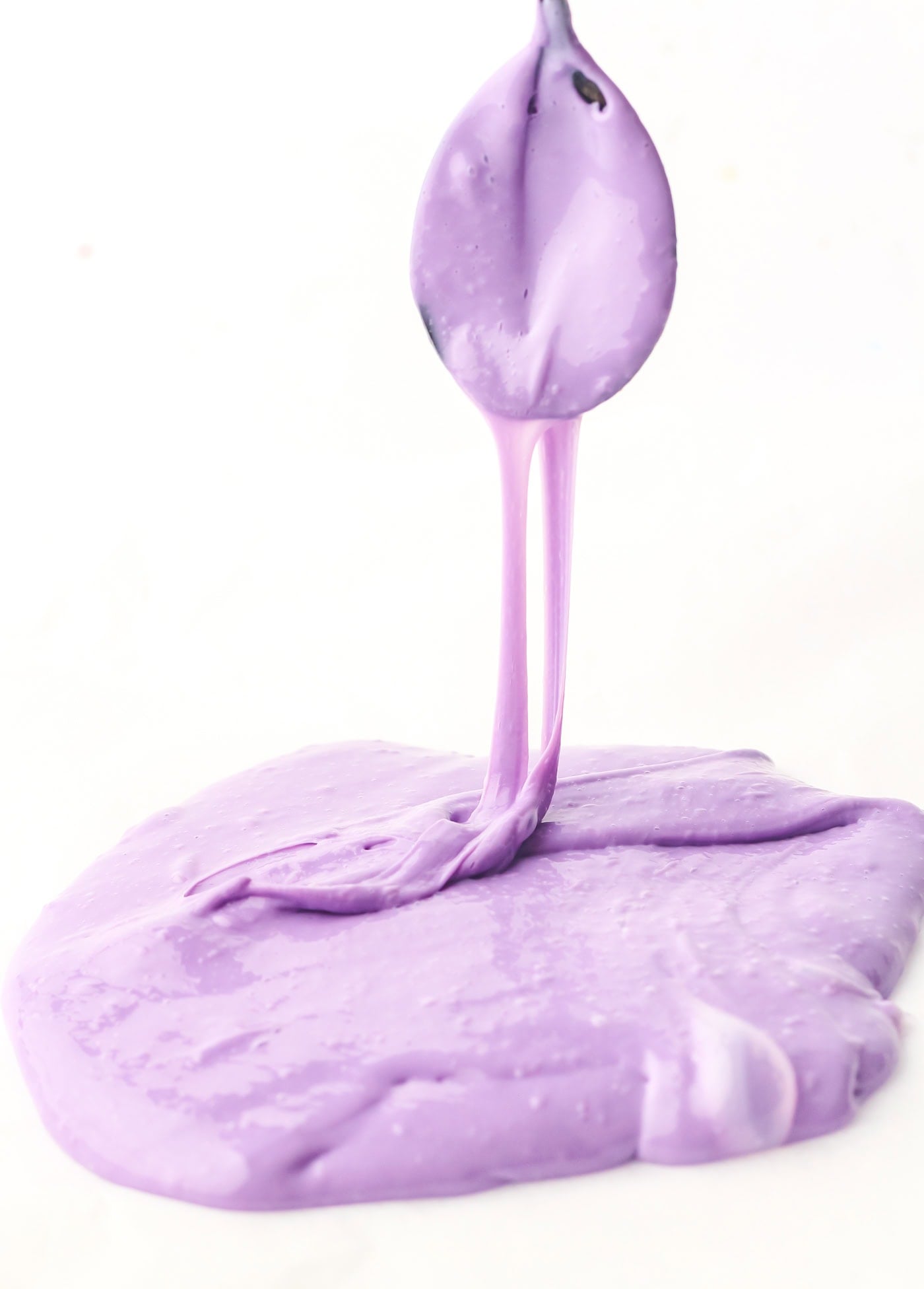 purple DIY sensory slime dripping off a spoon