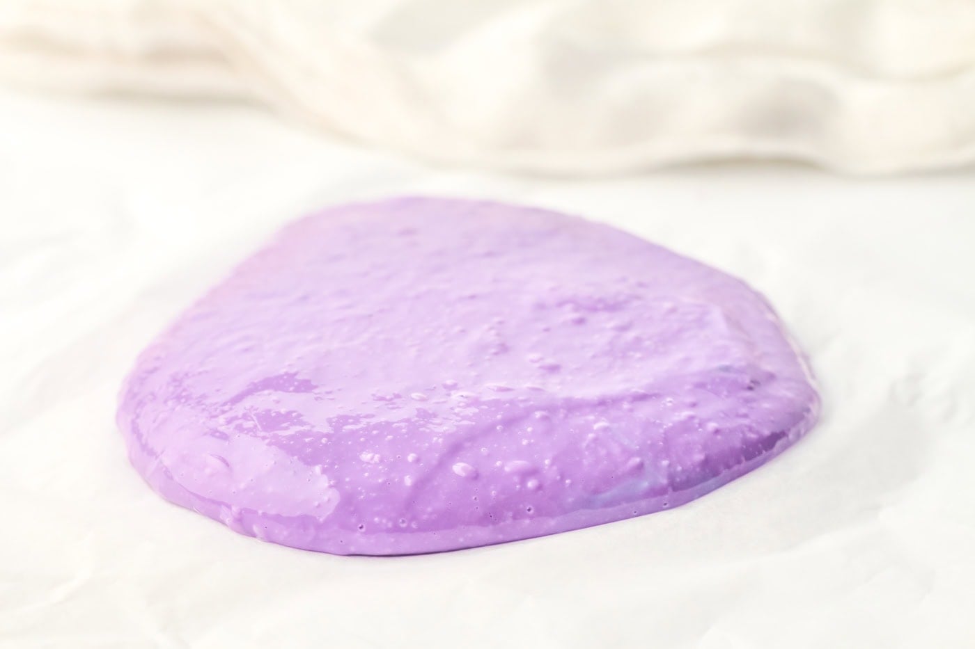 a puddle of diy purple slime on parchment paper