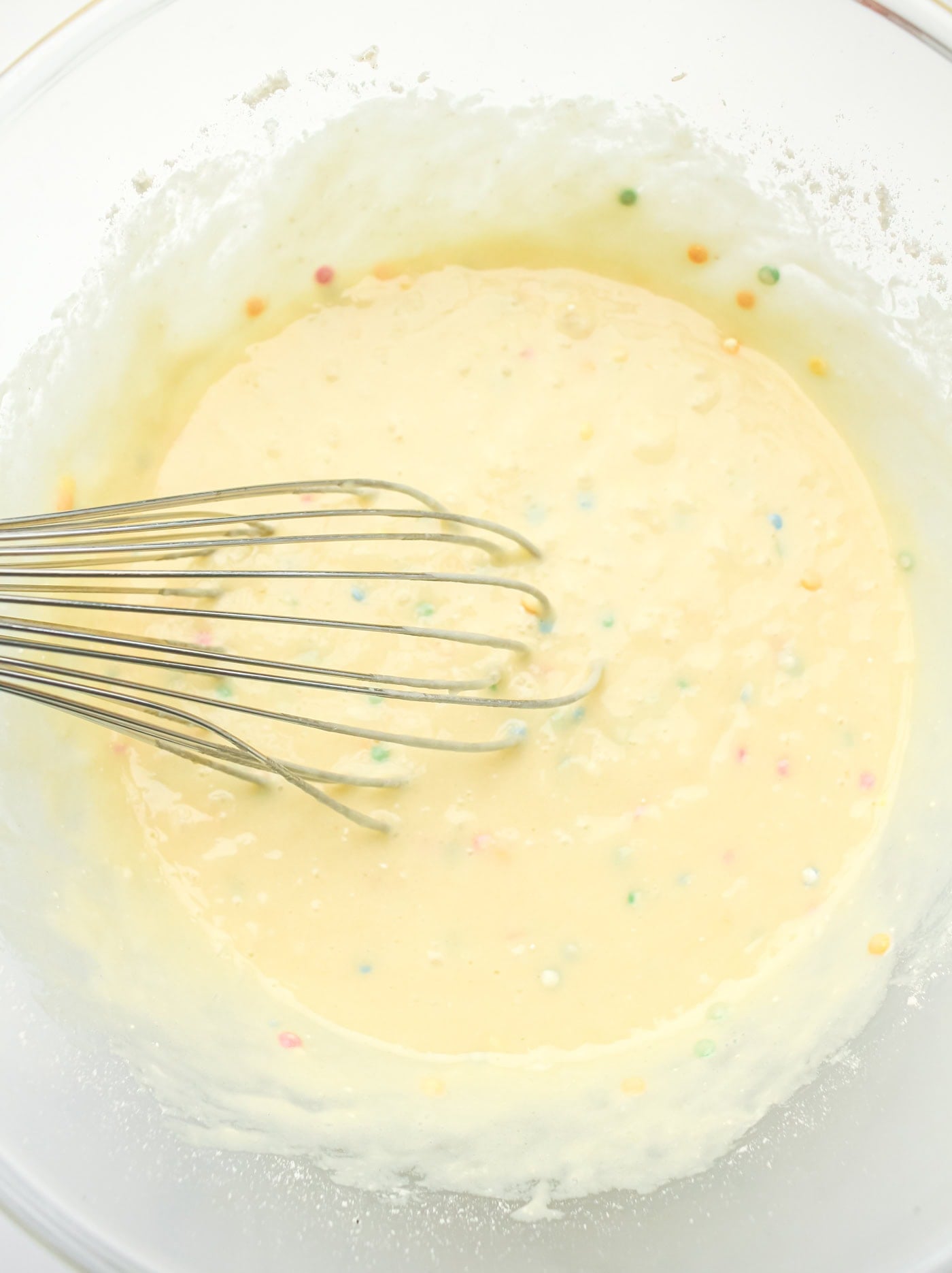 mixing batter for a gluten free DIY funfetti cake in a bowl