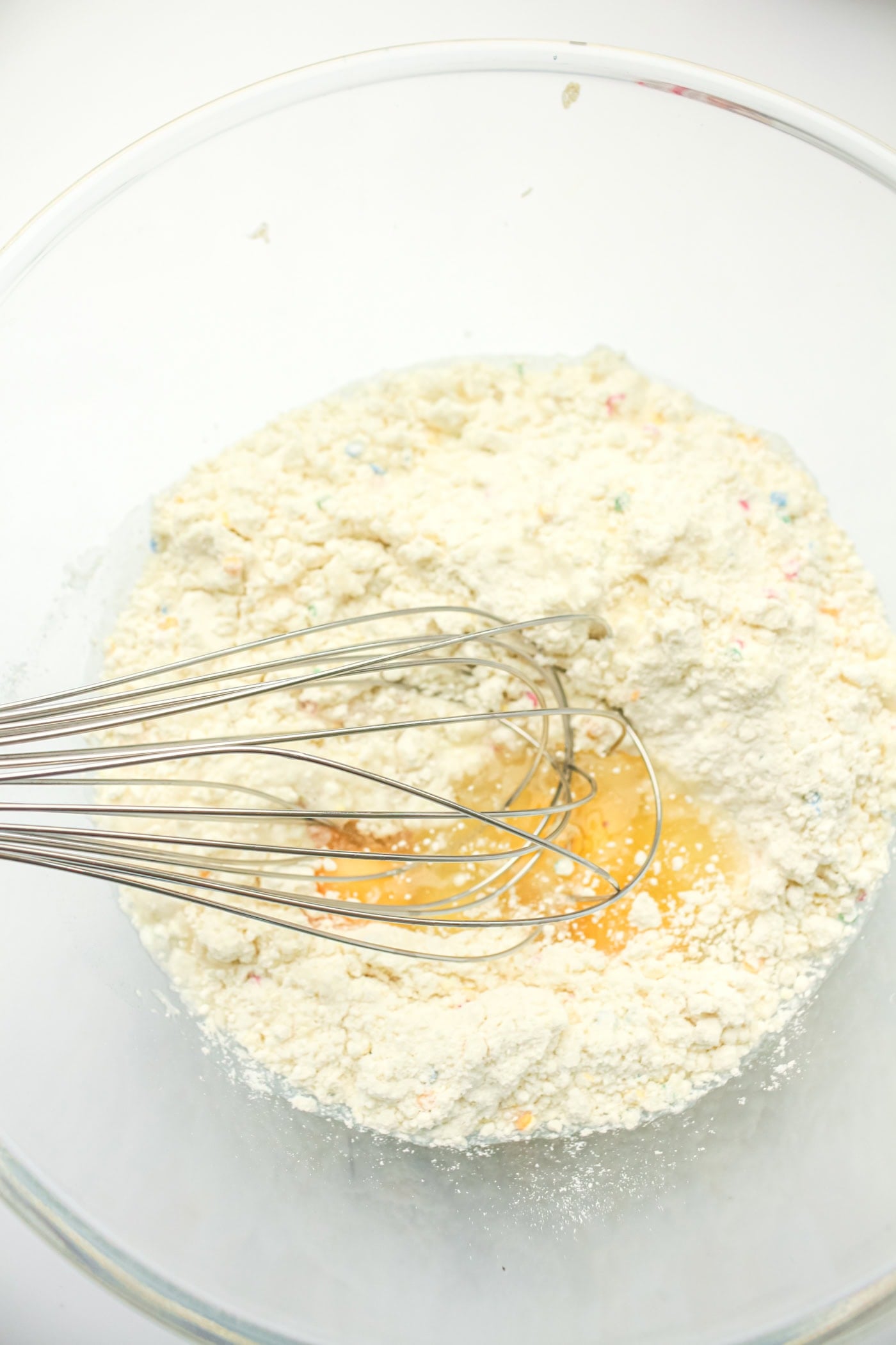 mixing batter for a gluten free DIY funfetti cake in a bowl