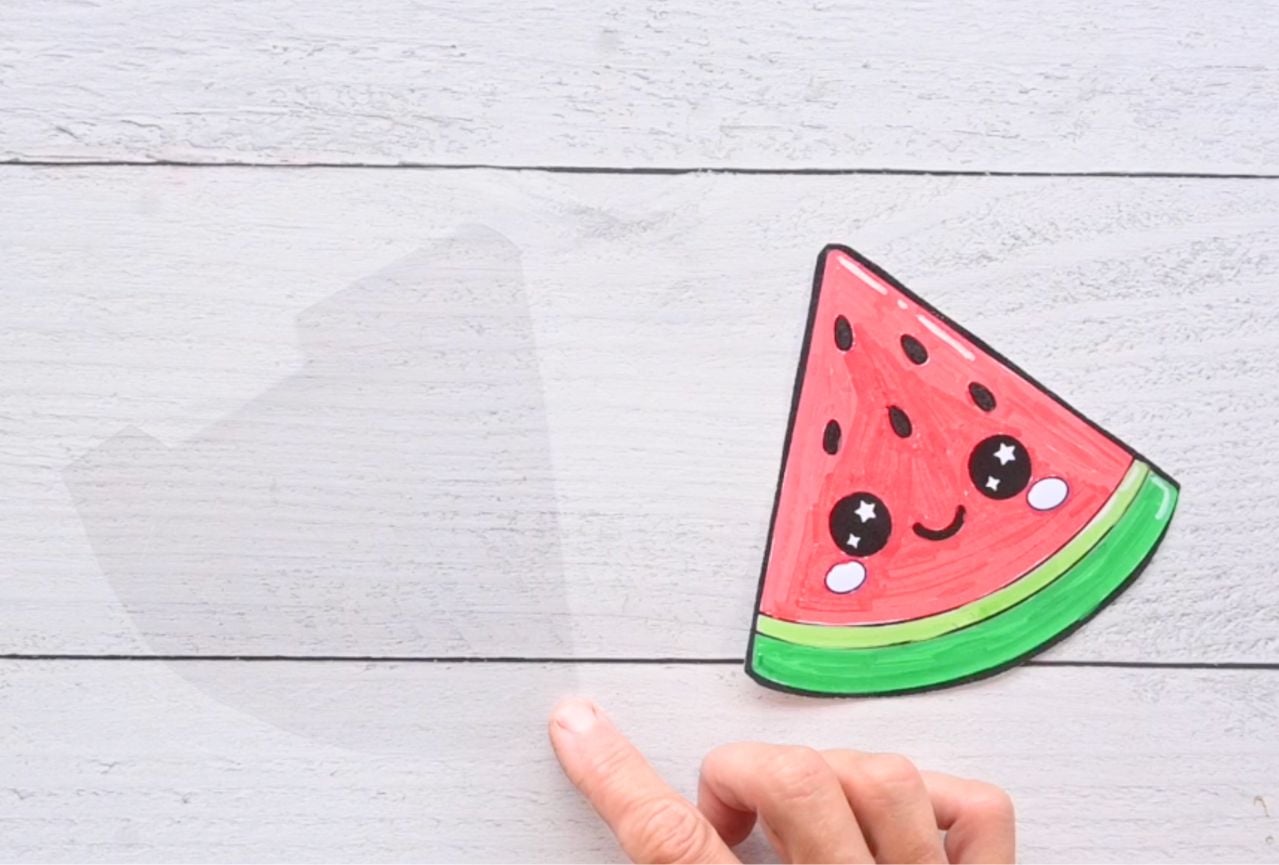 peeling backing off a piece of contact paper to make a paper squishy watermelon