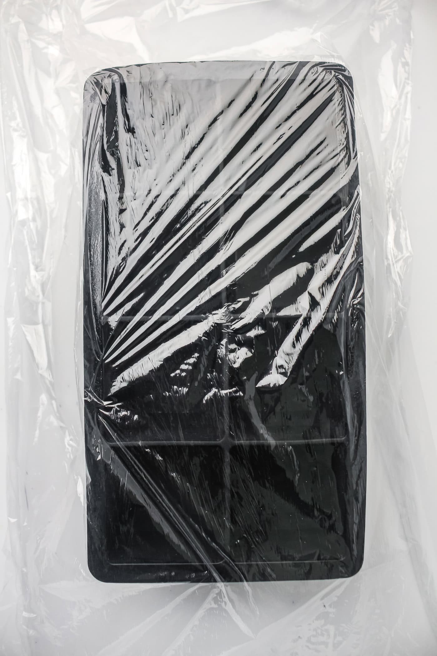 preparing an ice cube tray with plastic wrap to make ice cube tray sushi salmon rolls