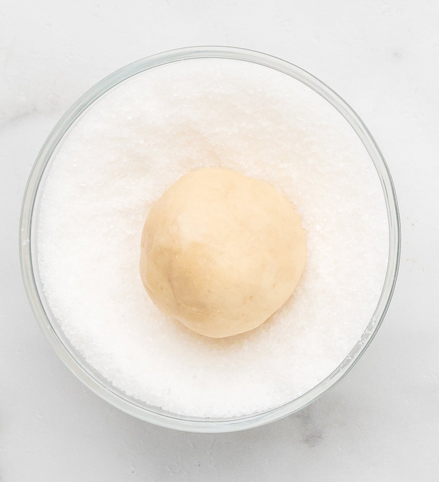 a ball of sourdough discard sugar cookie dough being roll din sugar