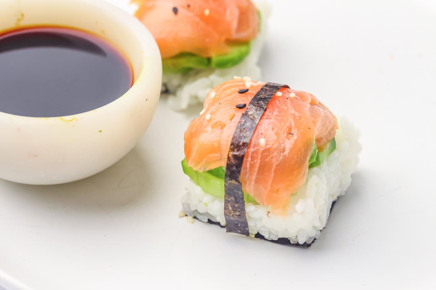 an ice cube tray sushi salmon roll with a seaweed wrap next to a bowl of soy sauce