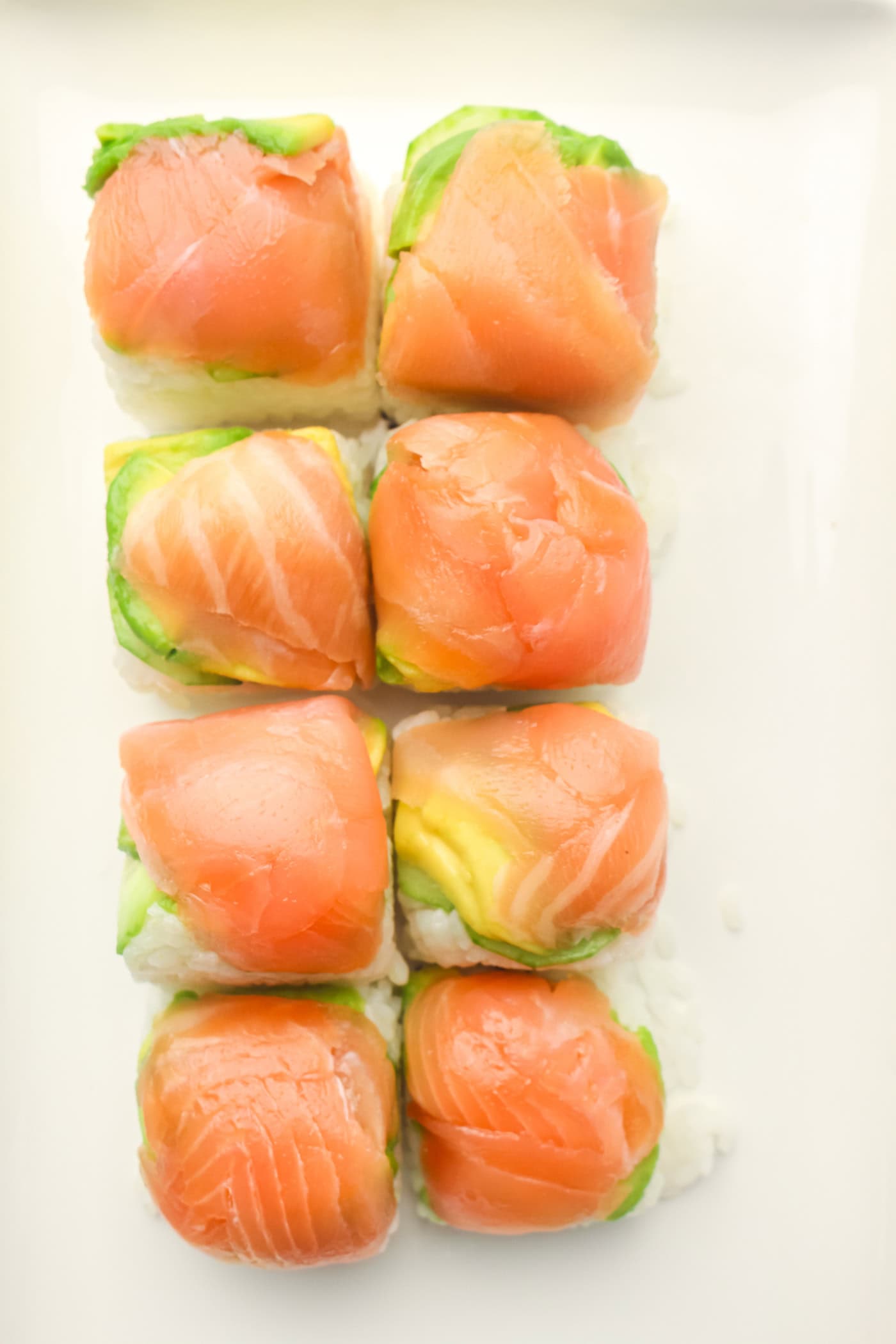 a white tray with ice cube tray sushi salmon rolls