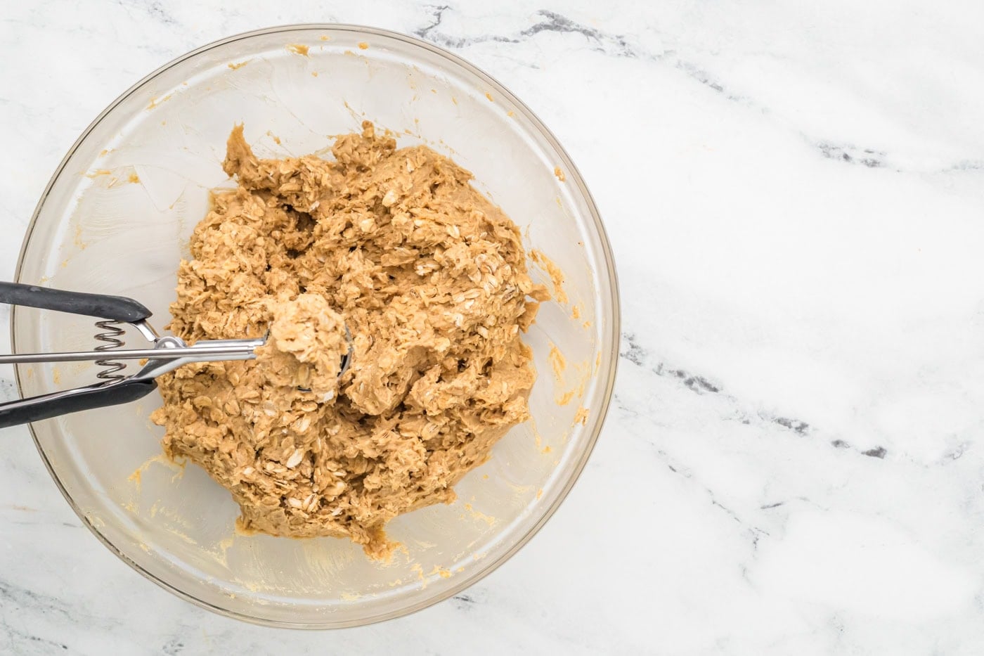 dough in a bowl with a cookie scoop for making homemade oatmeal cream pies