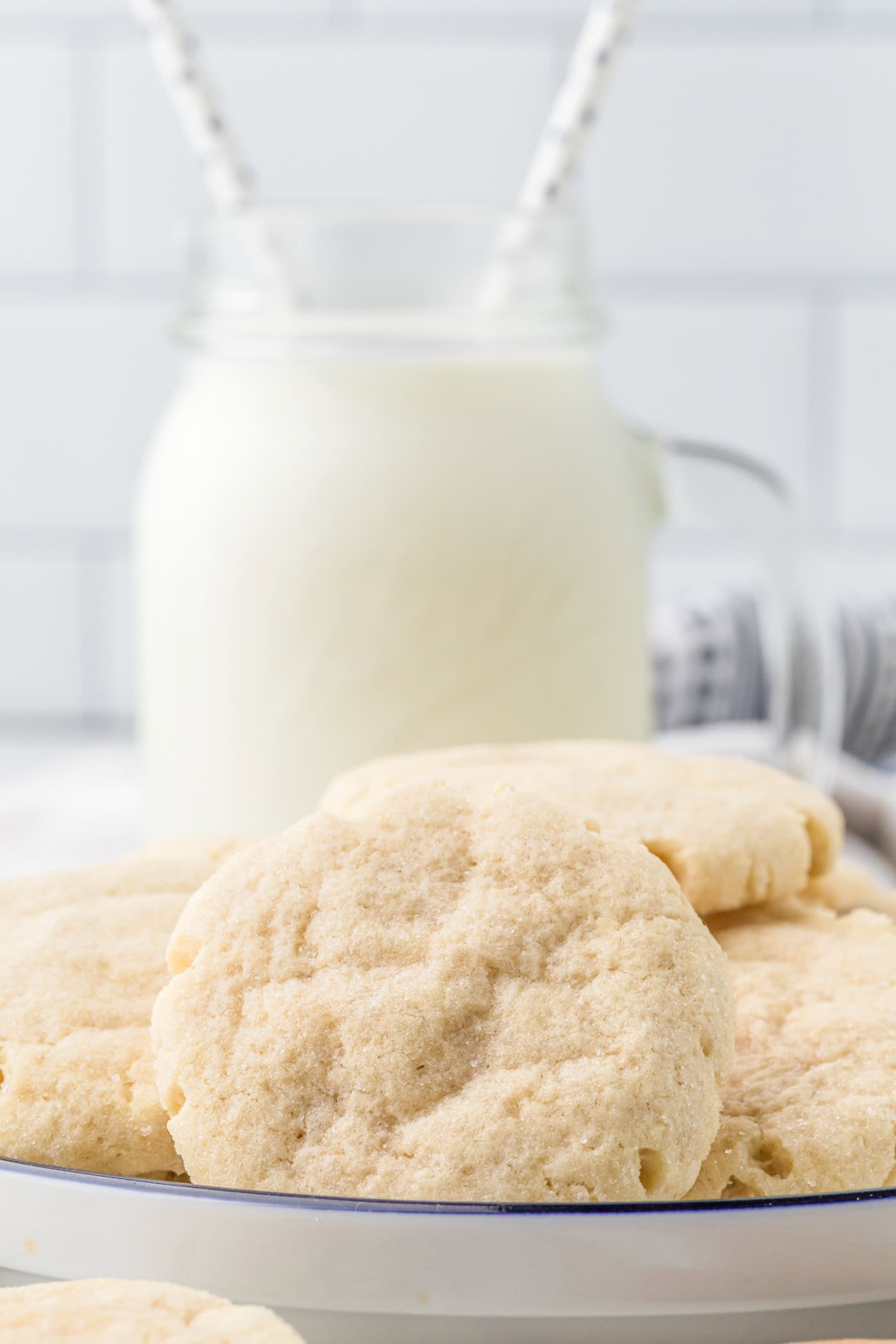 a plate of sourdough discard sugar cookies with a bottle of ilk in the background
