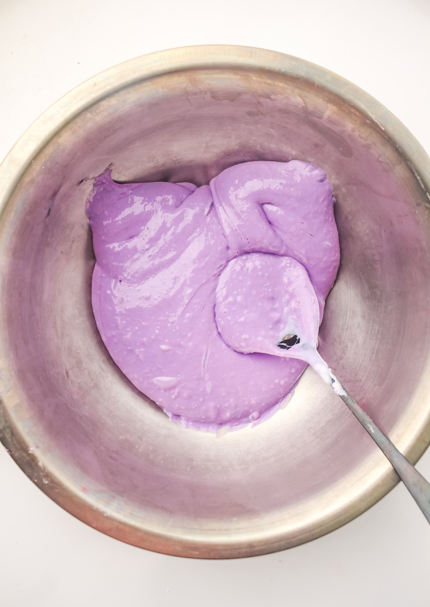 stirring purple DIY sensory slime in a bowl