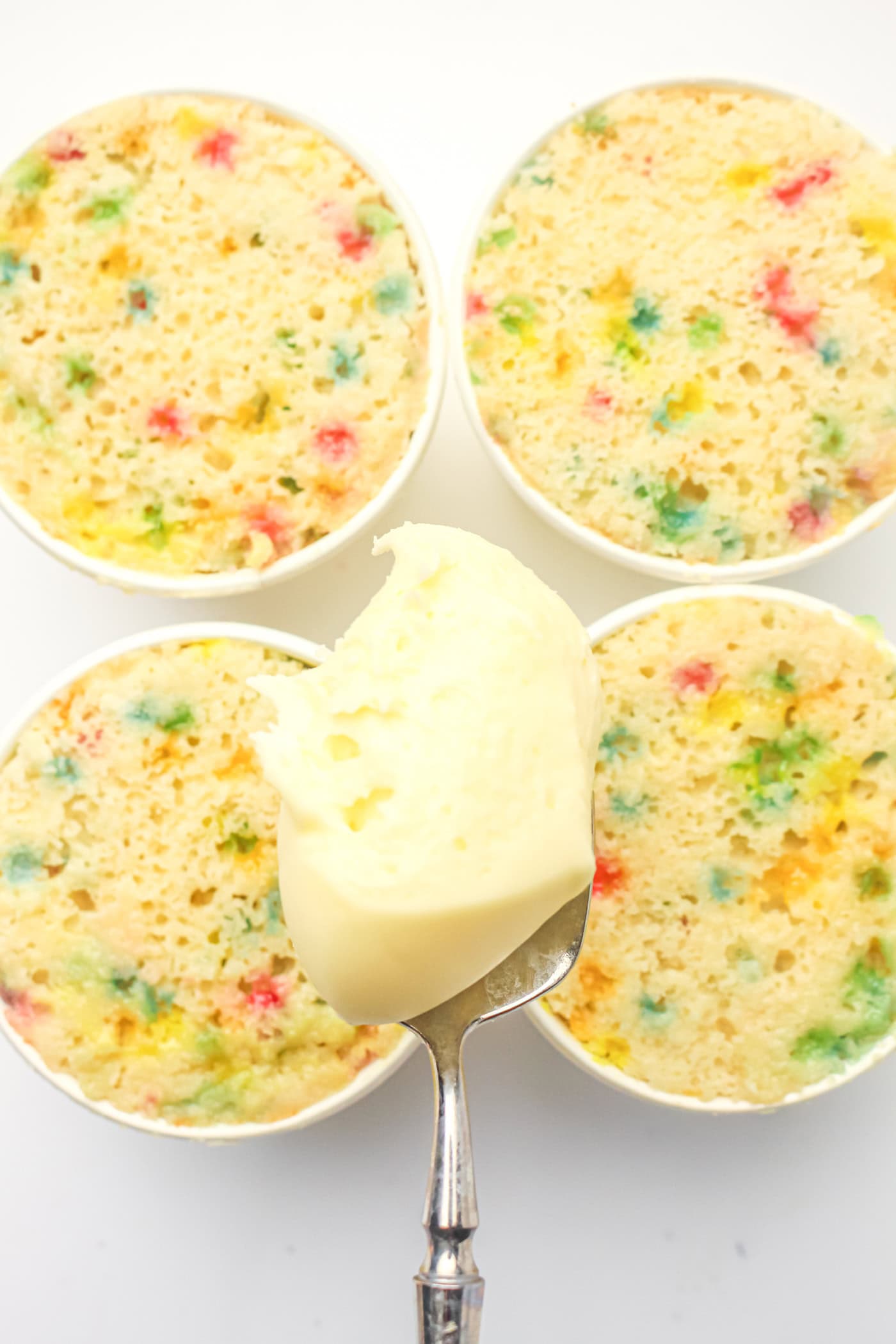adding frosting to gluten free dot cakes in paper cups