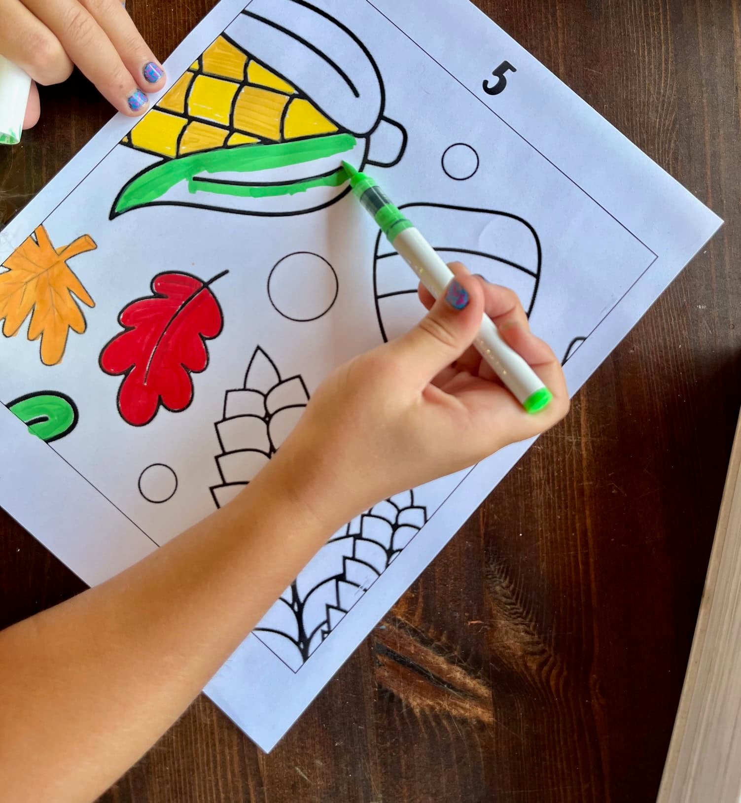a child's hadn't using a marker to color a page from a fall collaboration poster