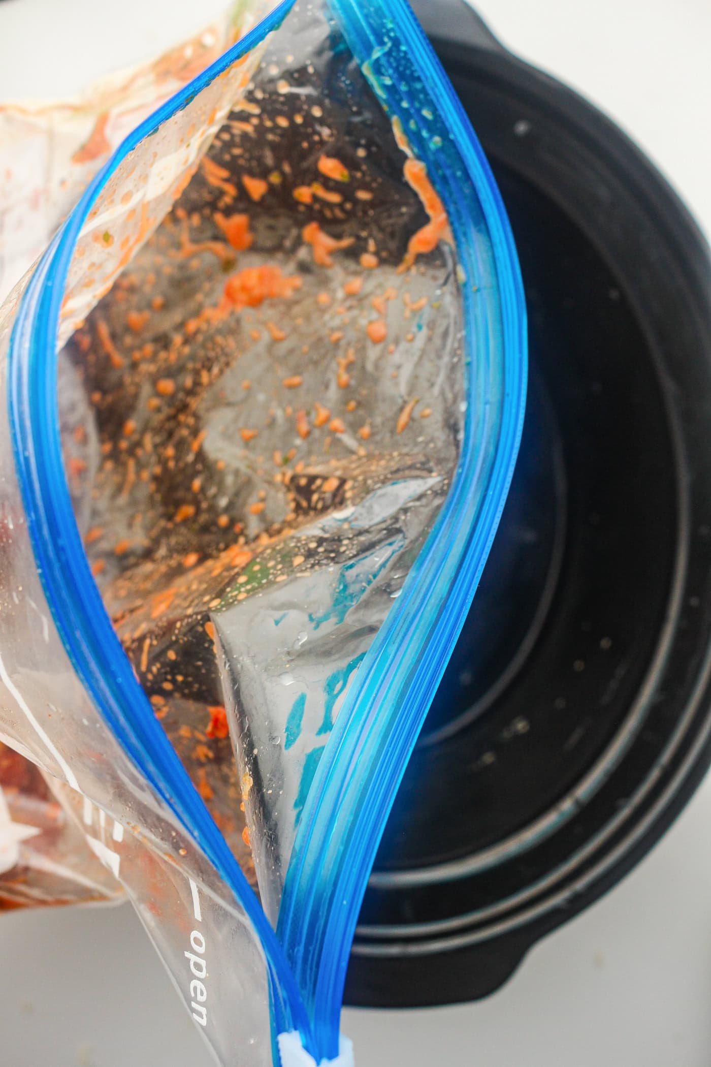 pouring a bag of salsa slow cooker chicken into a crock pot