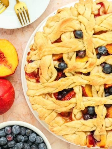 a baked peach and blueberry pie with a lattice top