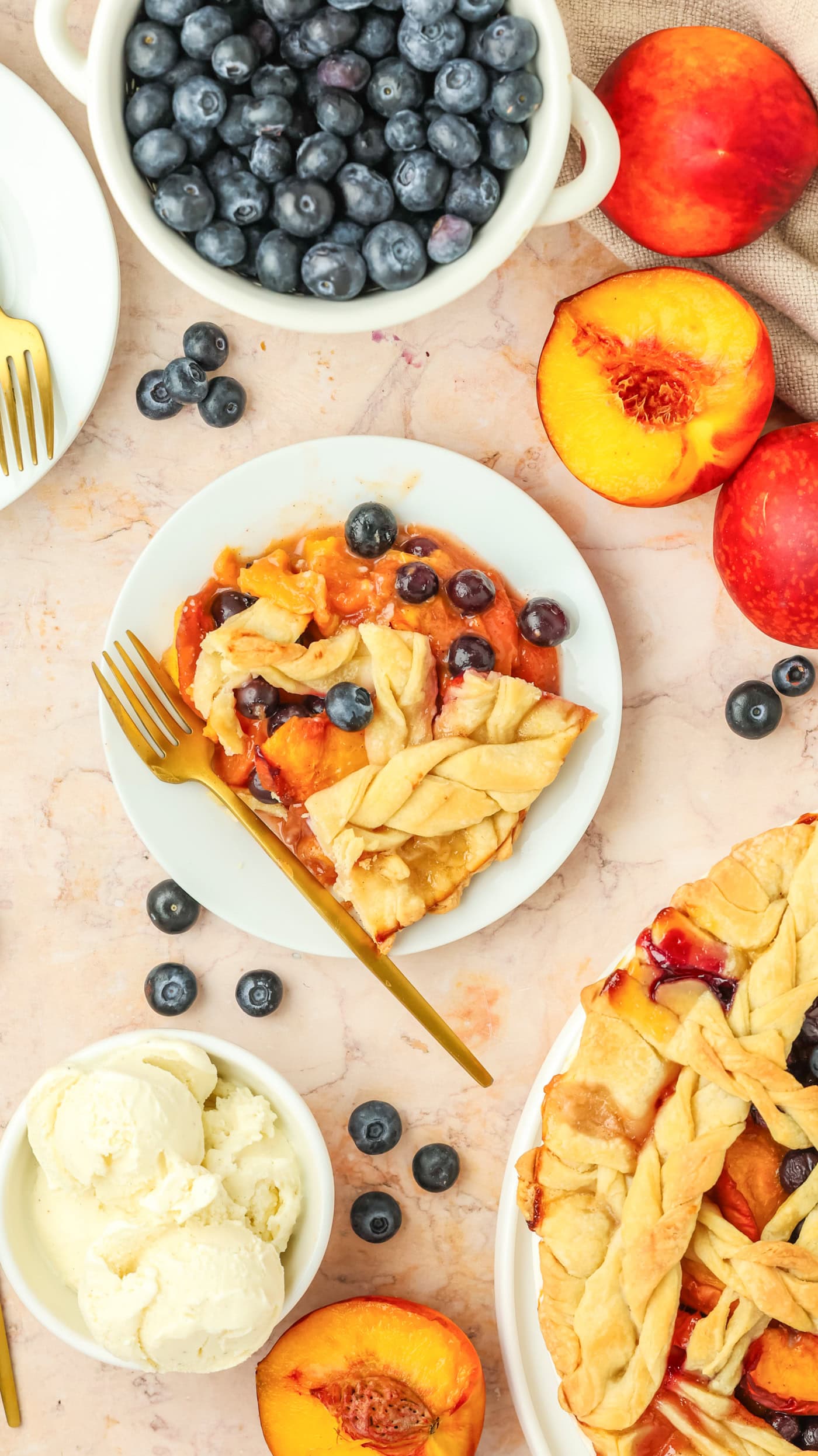a top down photo of a slice of blueberry peach pie next to a bowl of ice cream