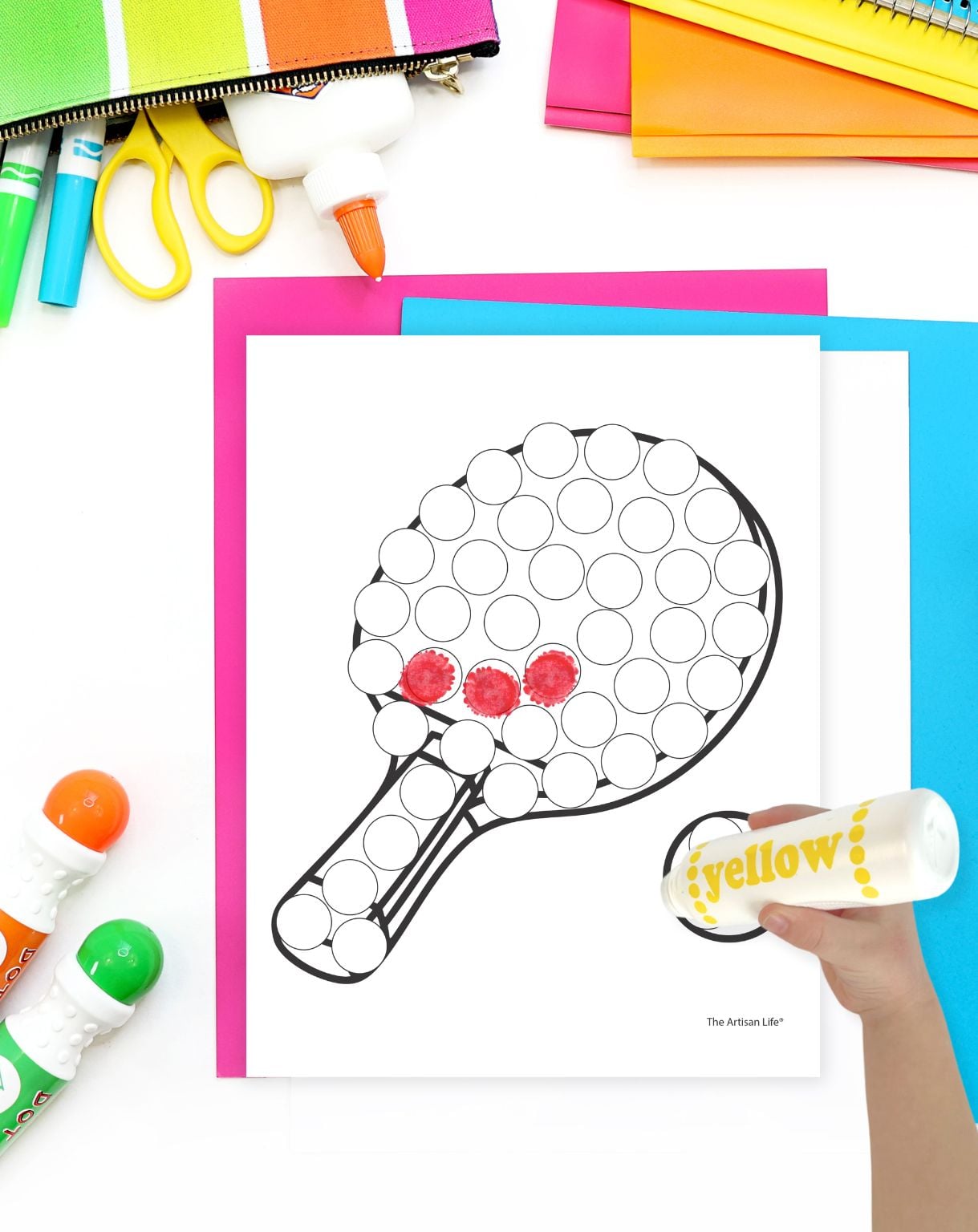 A child's hand holding a dot marker preparing to color a pickleball paddle dot marker coloring page