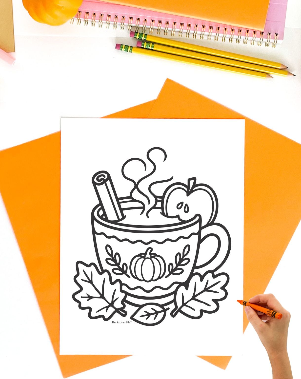 a hadn't with an orange crayon preparing to color an apple cider coloring pages