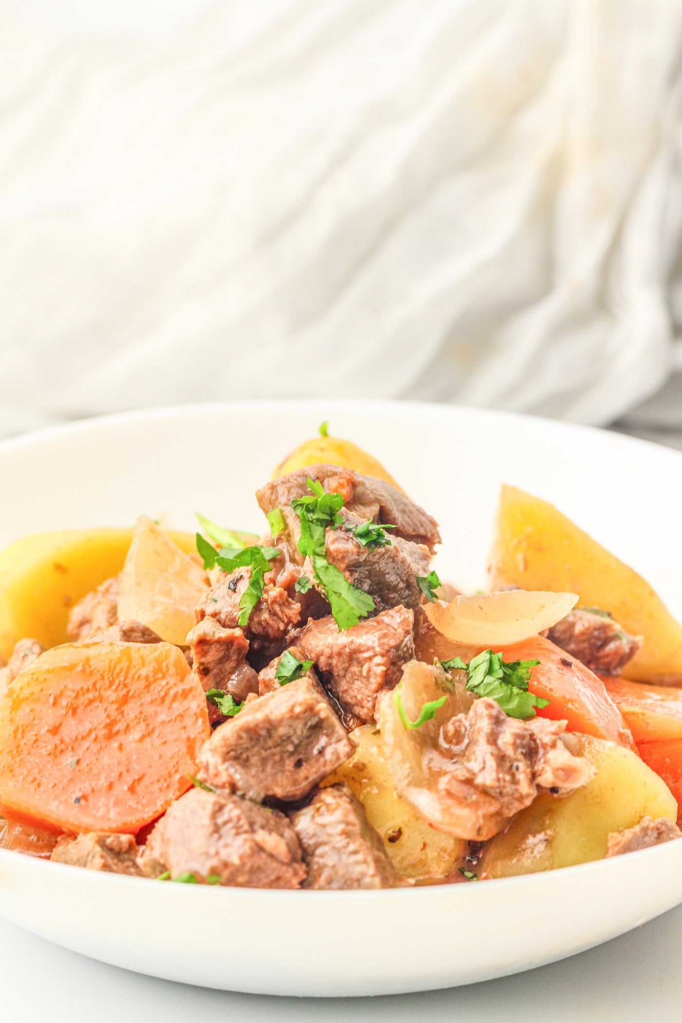 a bowl with slow cooker beef stew topped with parsley