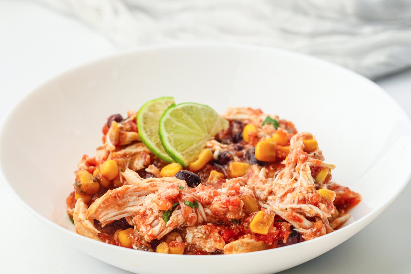shredded salsa slow cooker chicken in a bowl with lime slices