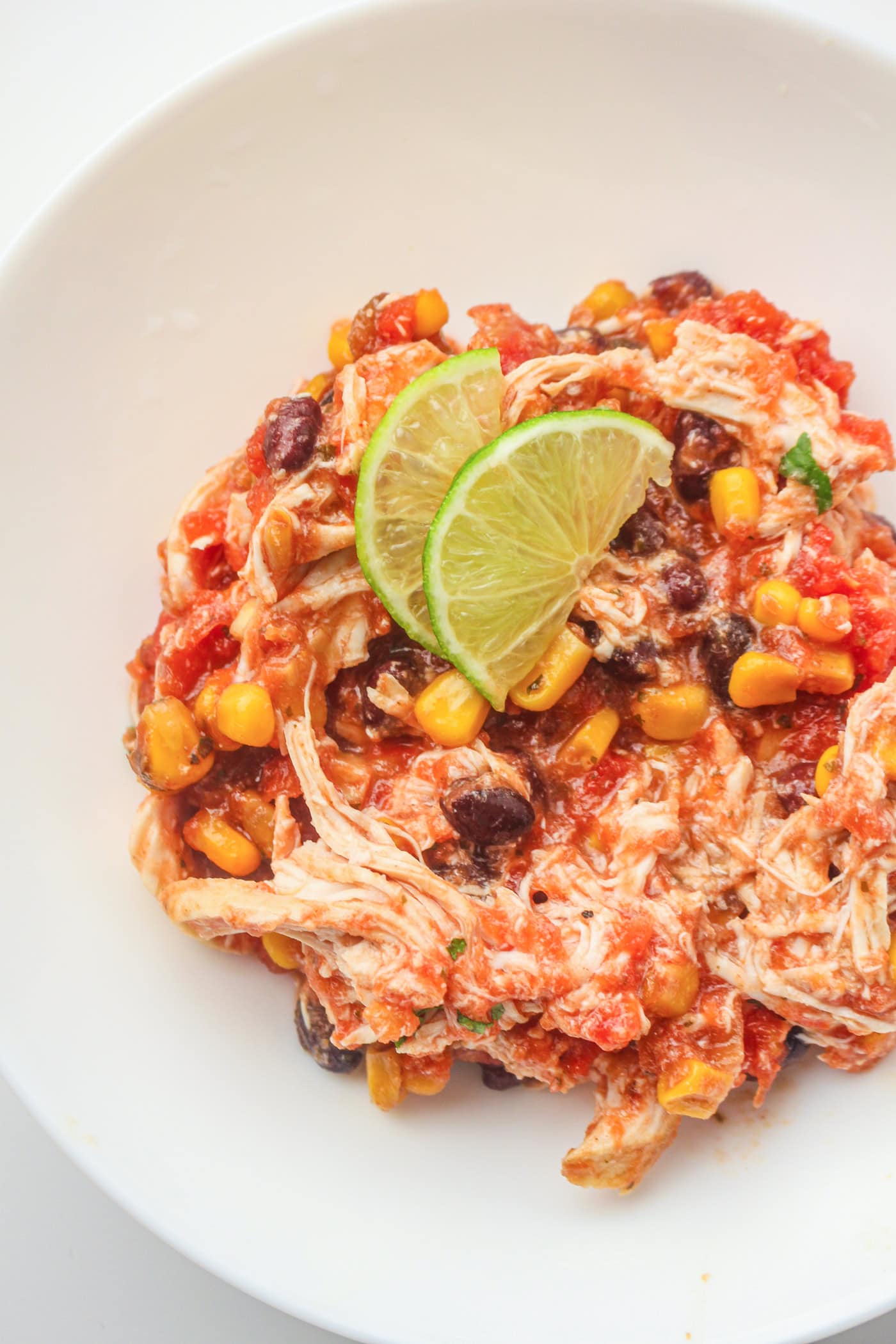 shredded salsa slow cooker chicken in a crockpot on a plate with a lime slice