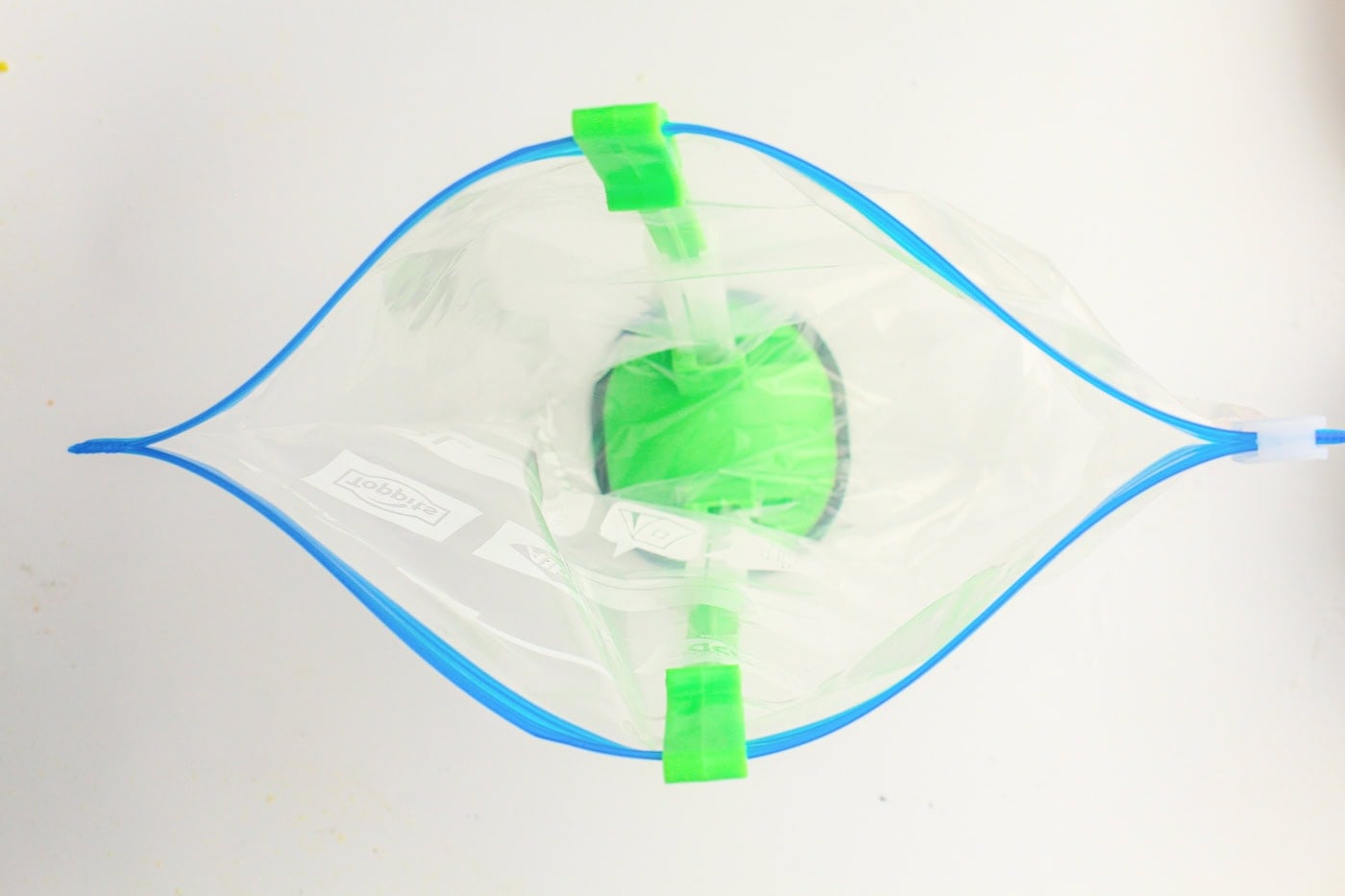 a green plastic gallon bag holder holding an empty gallon bag