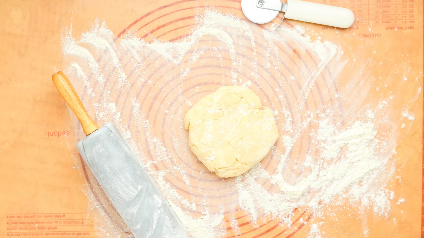a ball of pie crust dough on a dough rolling mat