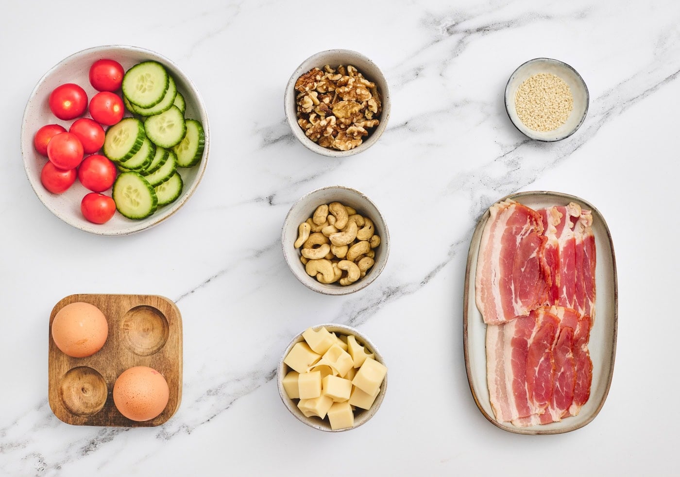 top down photo of veggies, nuts, cheese, bacon, and eggs for making a kids bento lunchbox