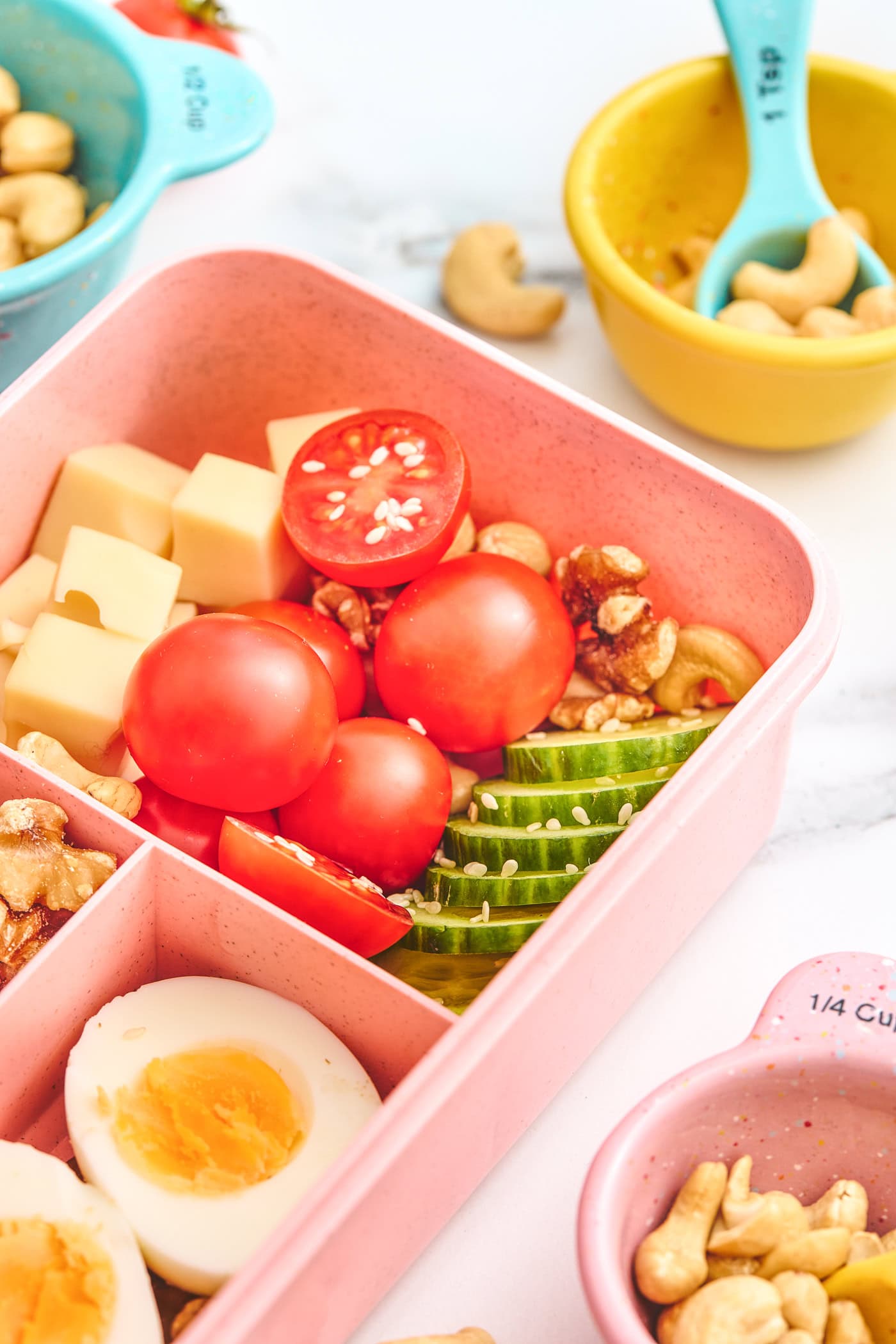 a close up photo of a child's bento box with veggies, nuts, and cheese