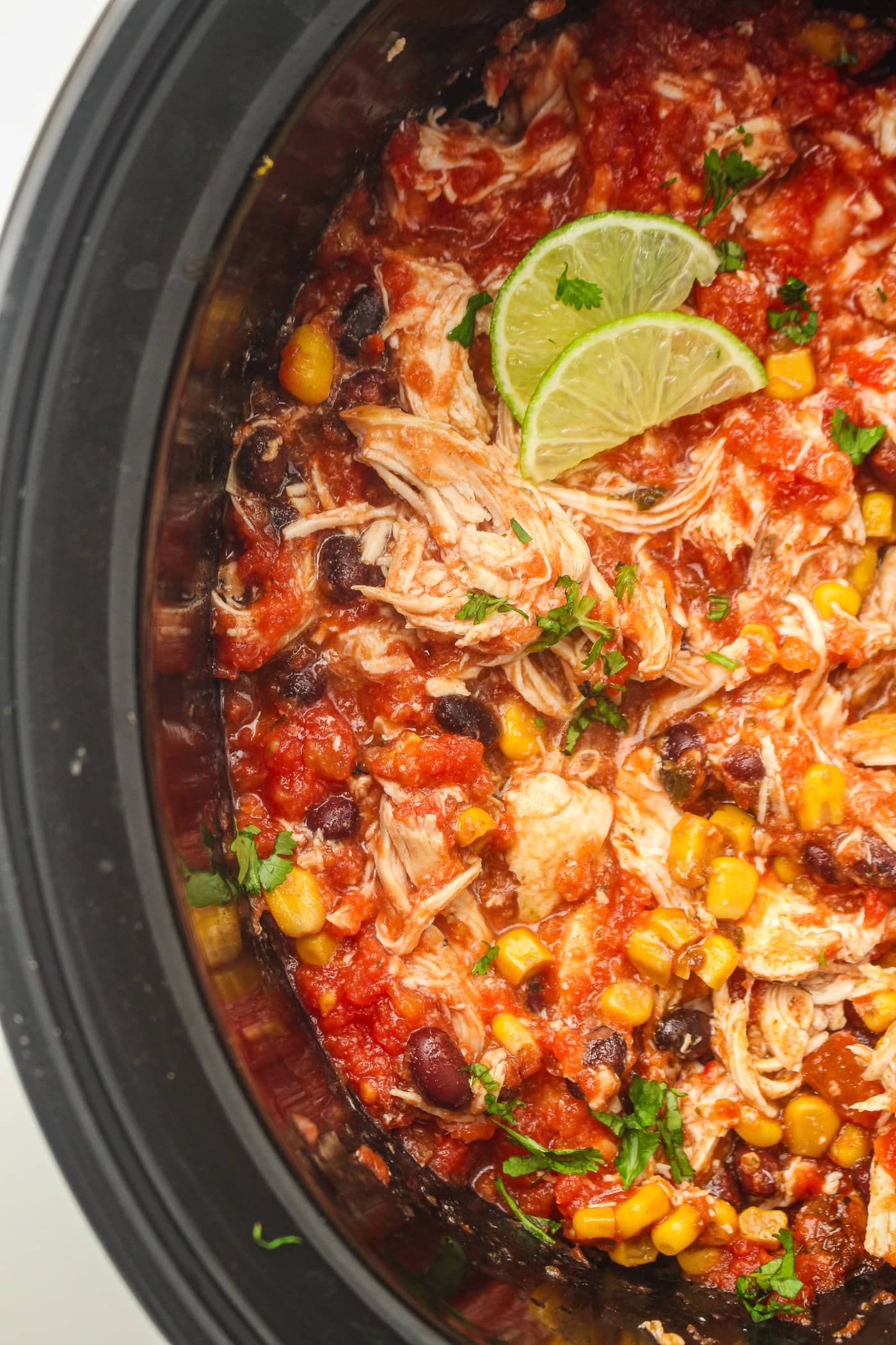 shredded salsa slow cooker chicken in a crockpot with lime and cilantro