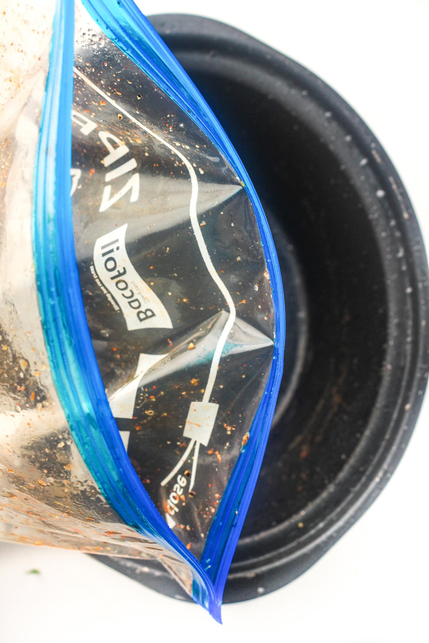 dumping a ziplock bag of honey bbq chicken ingredients into a slow cooker crock