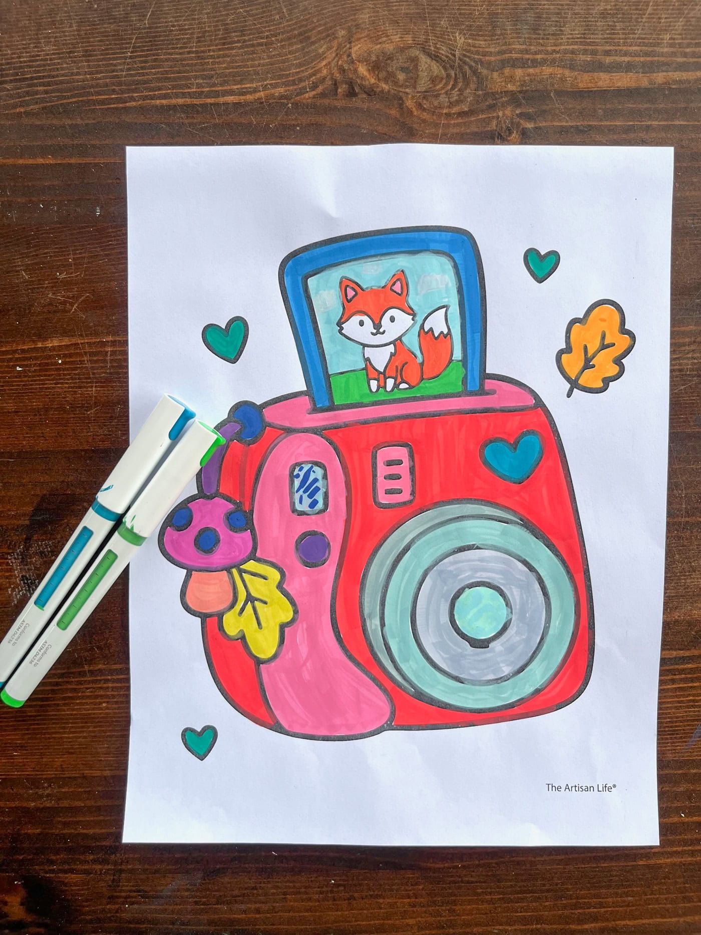 two paint markers with an instant style camera printing a photo of a fox