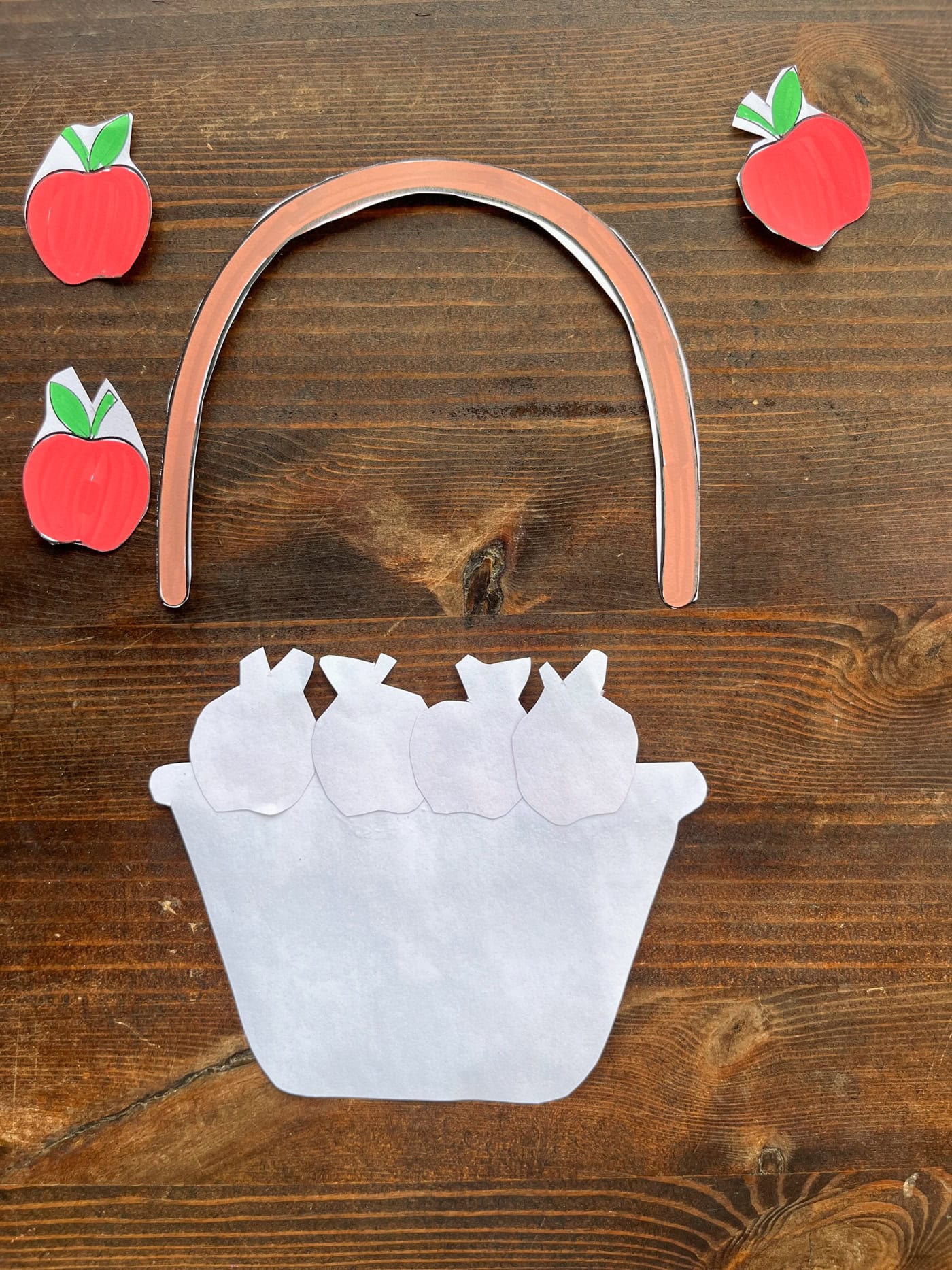 gluing apples to the back of a cut and paste apple basket craft