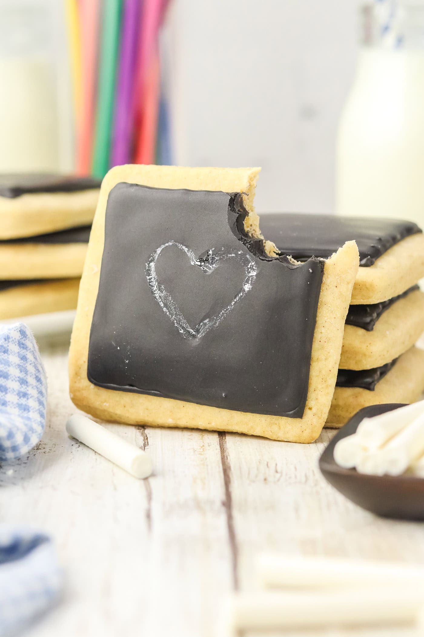 a square chalkboard sugar cookie with a heart on it and a bite removed