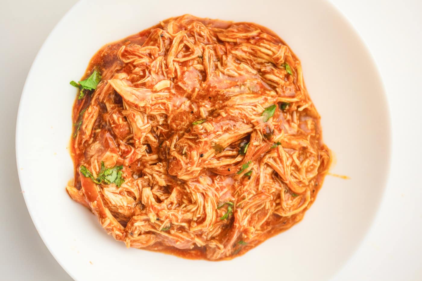 a top down photo of a bowl of slow cooker shredded honey bbq chicken