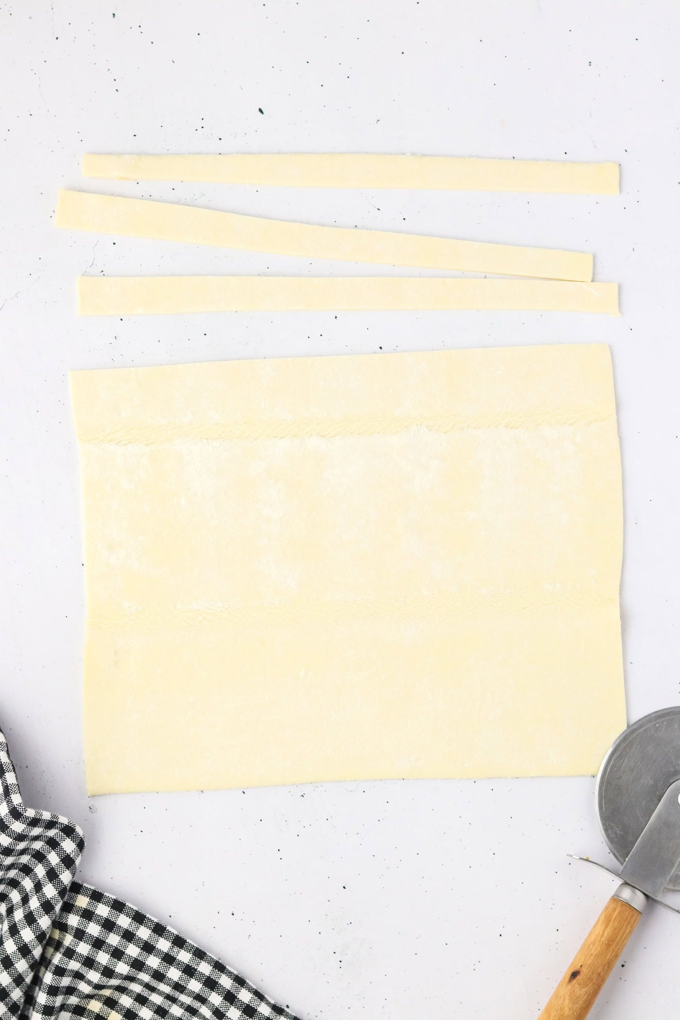 cutting strips of puff pastry with a pizza wheel