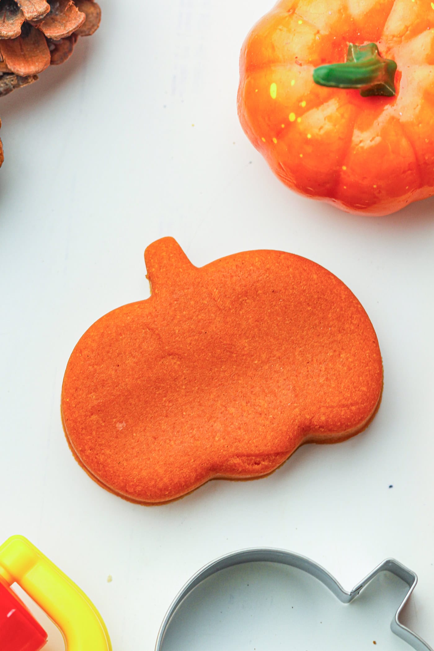 A cut out of an orange play dough pumpkin with a cookie cutter