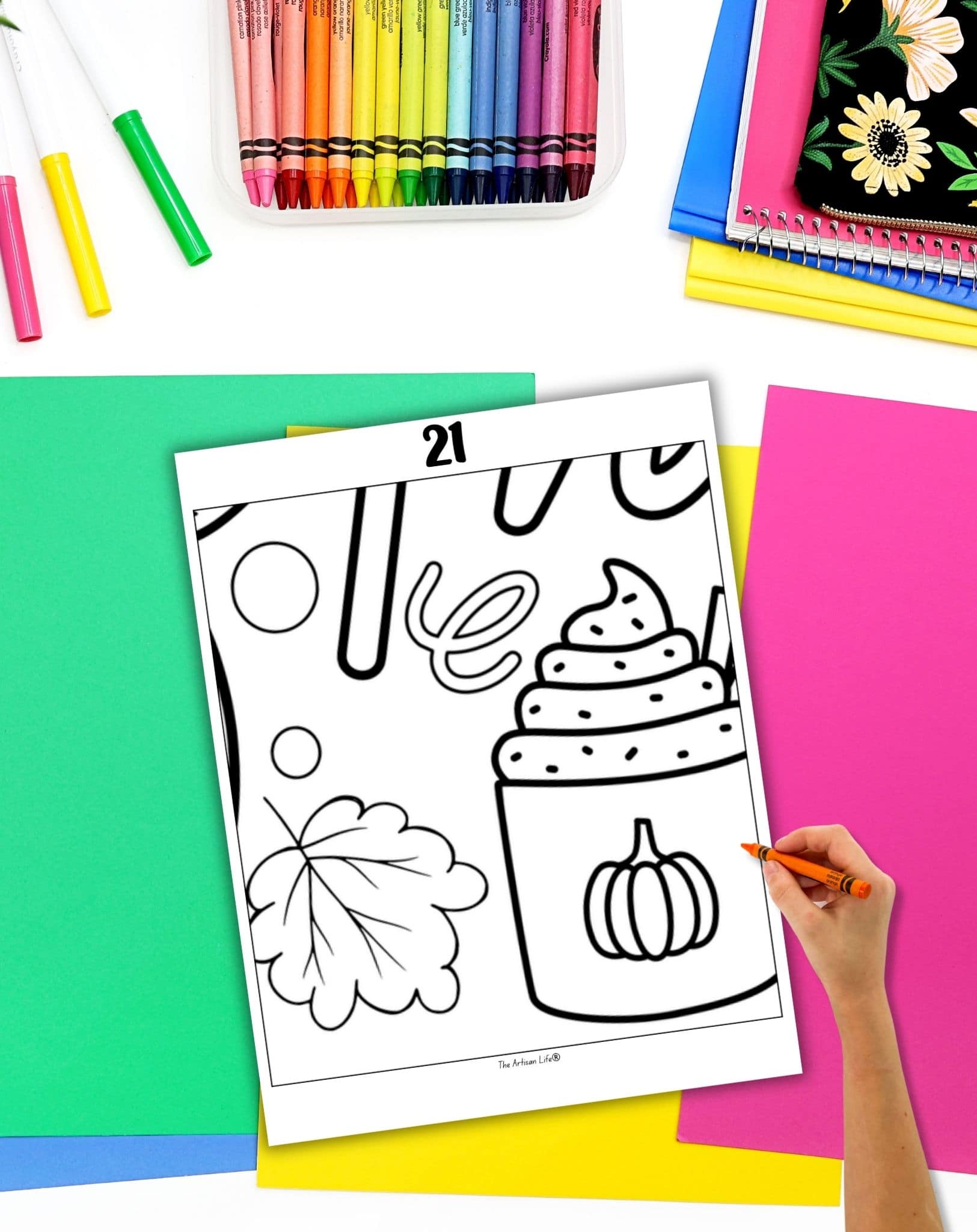 a hand with an orange crayon preparing to color a Thanksgiving collaborative poster sheet with a hot chocolate mug