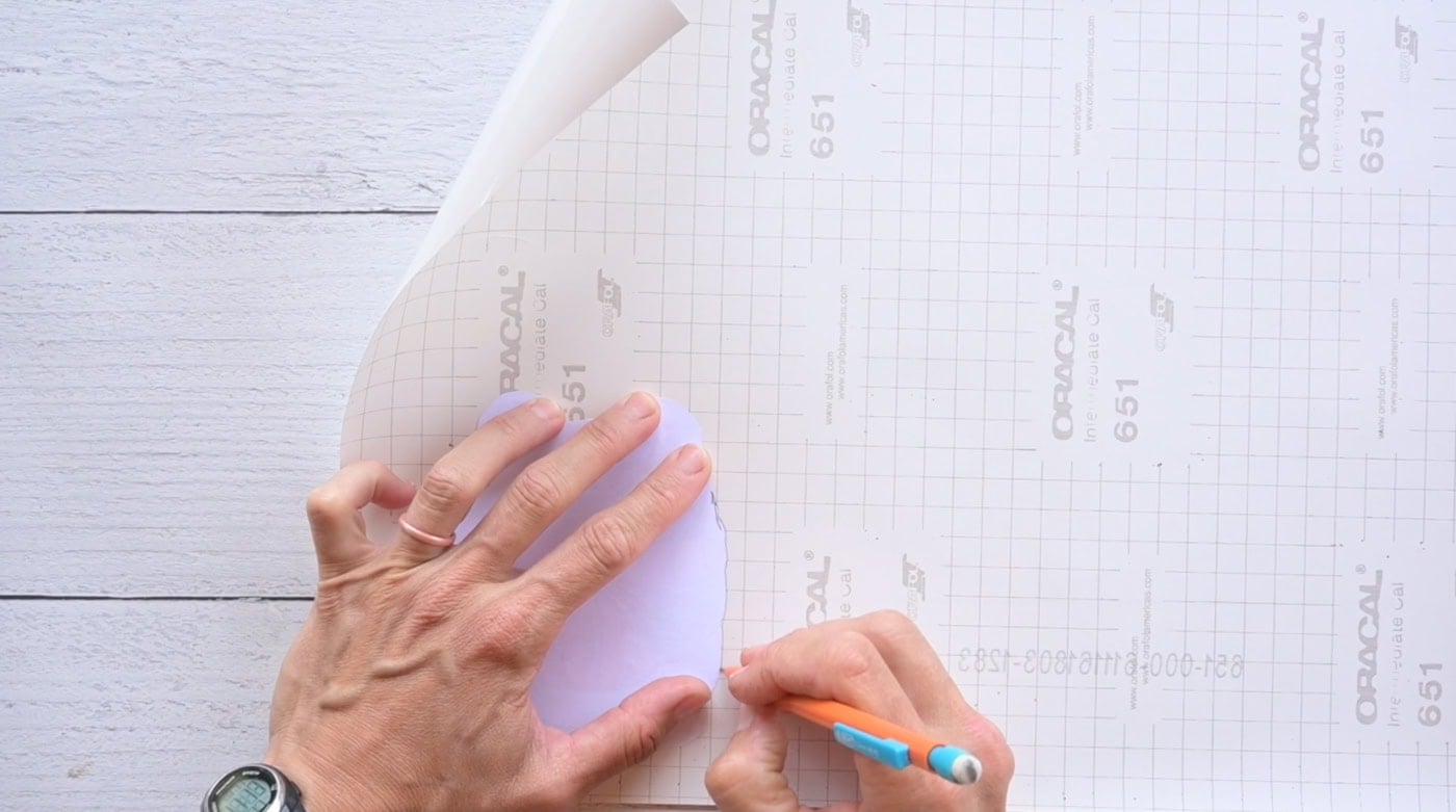 tracing the shape of a frog onto the back of contact paper to make a fall squishy