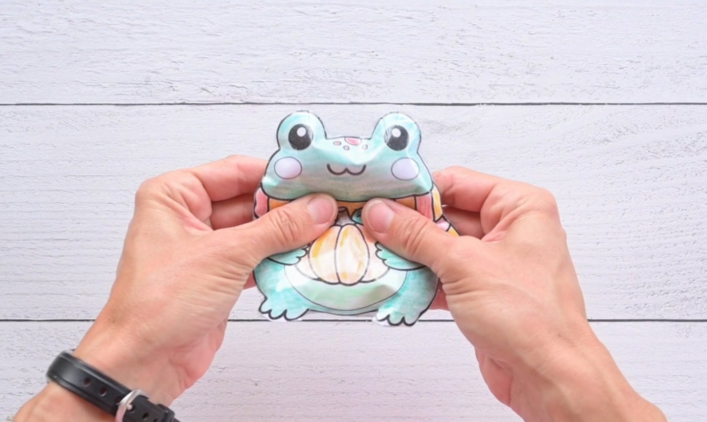 hands squishing a fall frog paper squishy