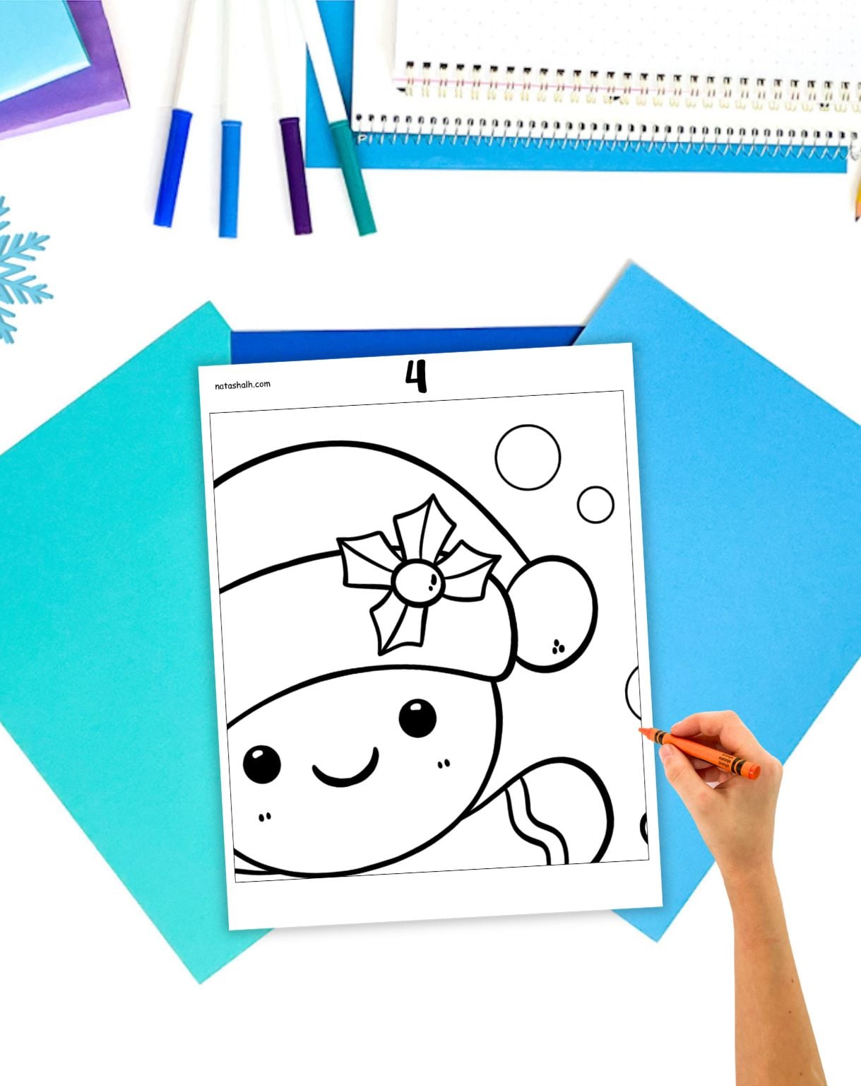a hand with a crayon preparing to color a collaborative poster coloring page with a gingerbread man